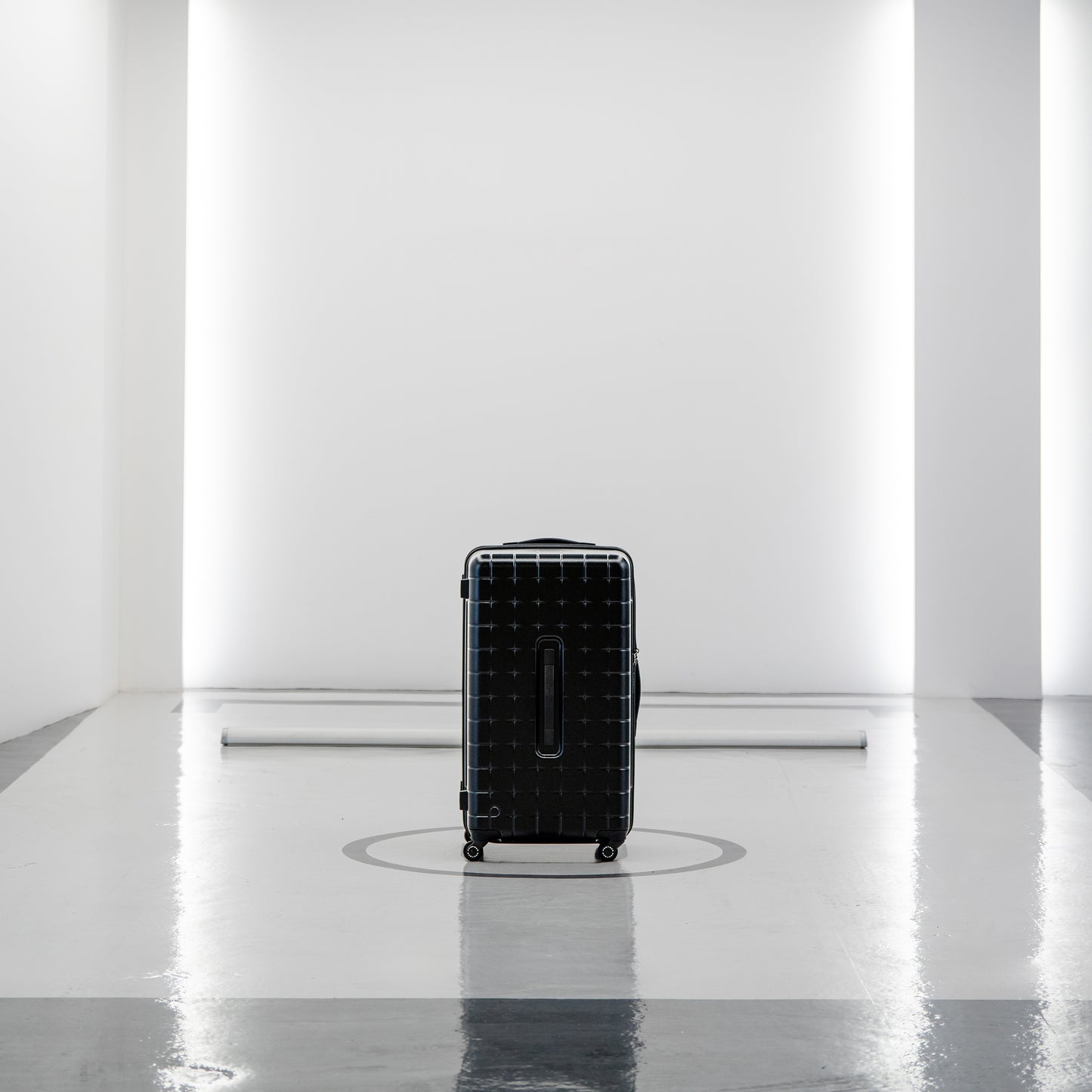 Black PROTECA 360G4 hard-shell suitcase standing in a minimalist modern studio space