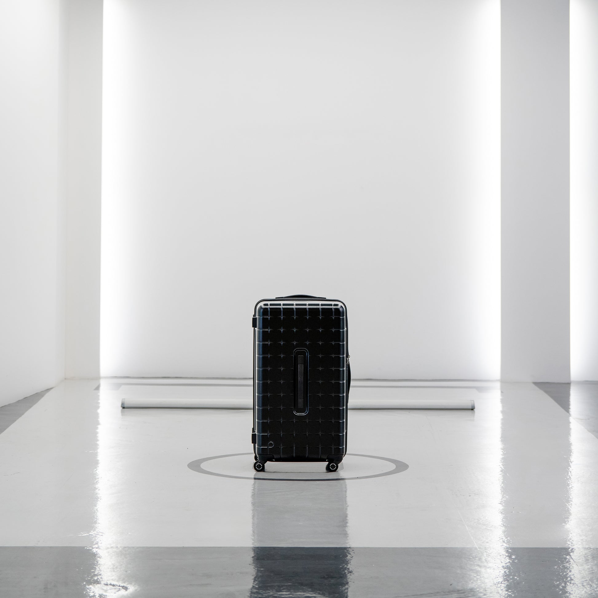 Black PROTECA 360G4 hard-shell suitcase standing in a minimalist modern studio space