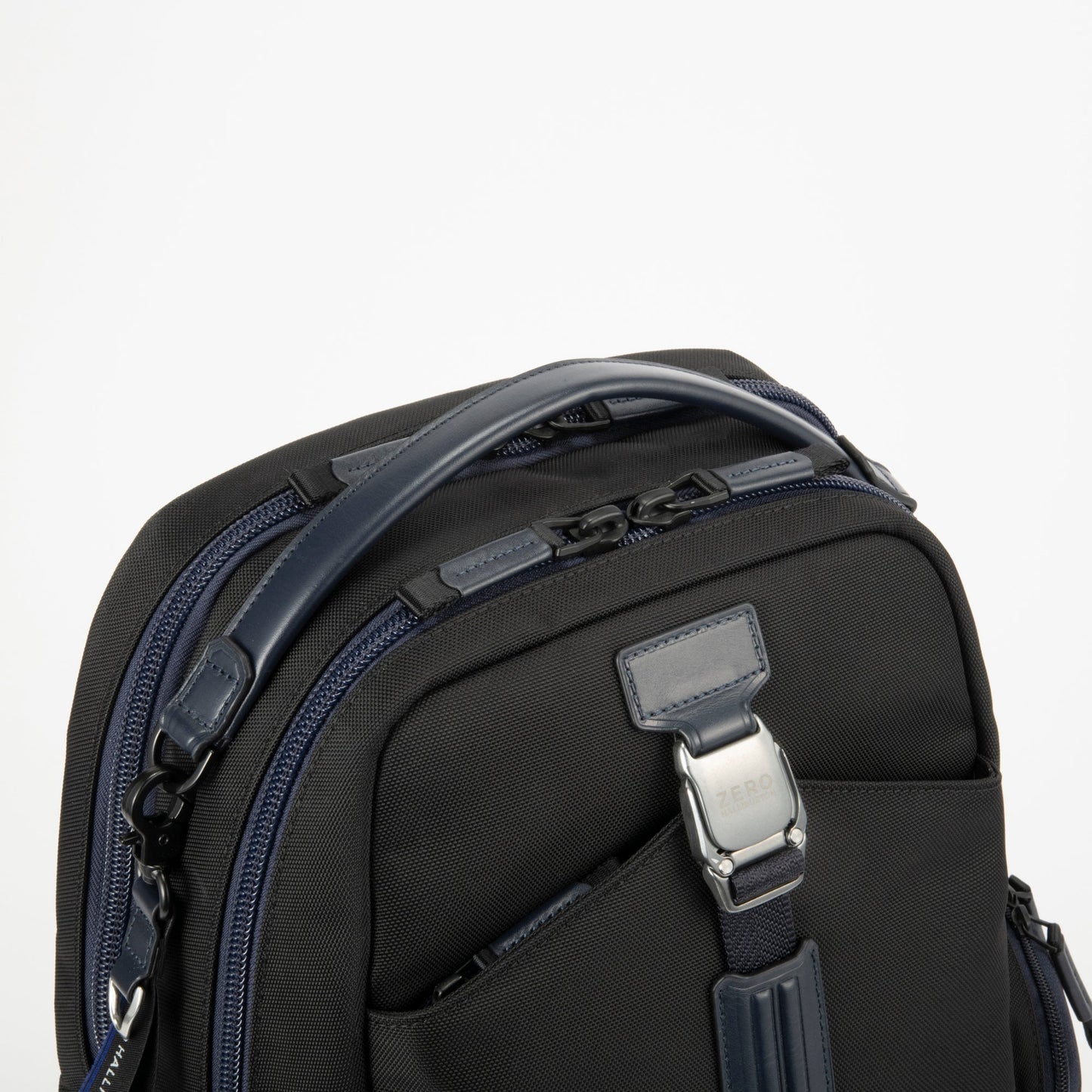 Navy - backpack with multiple zippers and a shoulder strap on a light gray background
