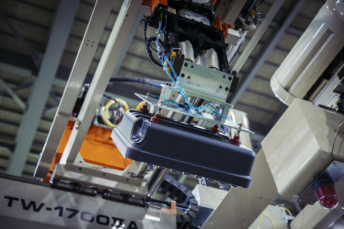 Robotic arm handling molded luggage shell part during automated production process